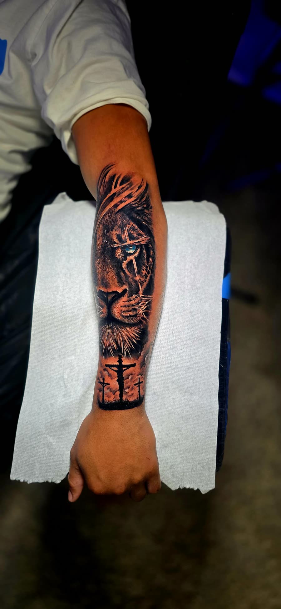 León con ojo azul y tres cruces en antebrazo