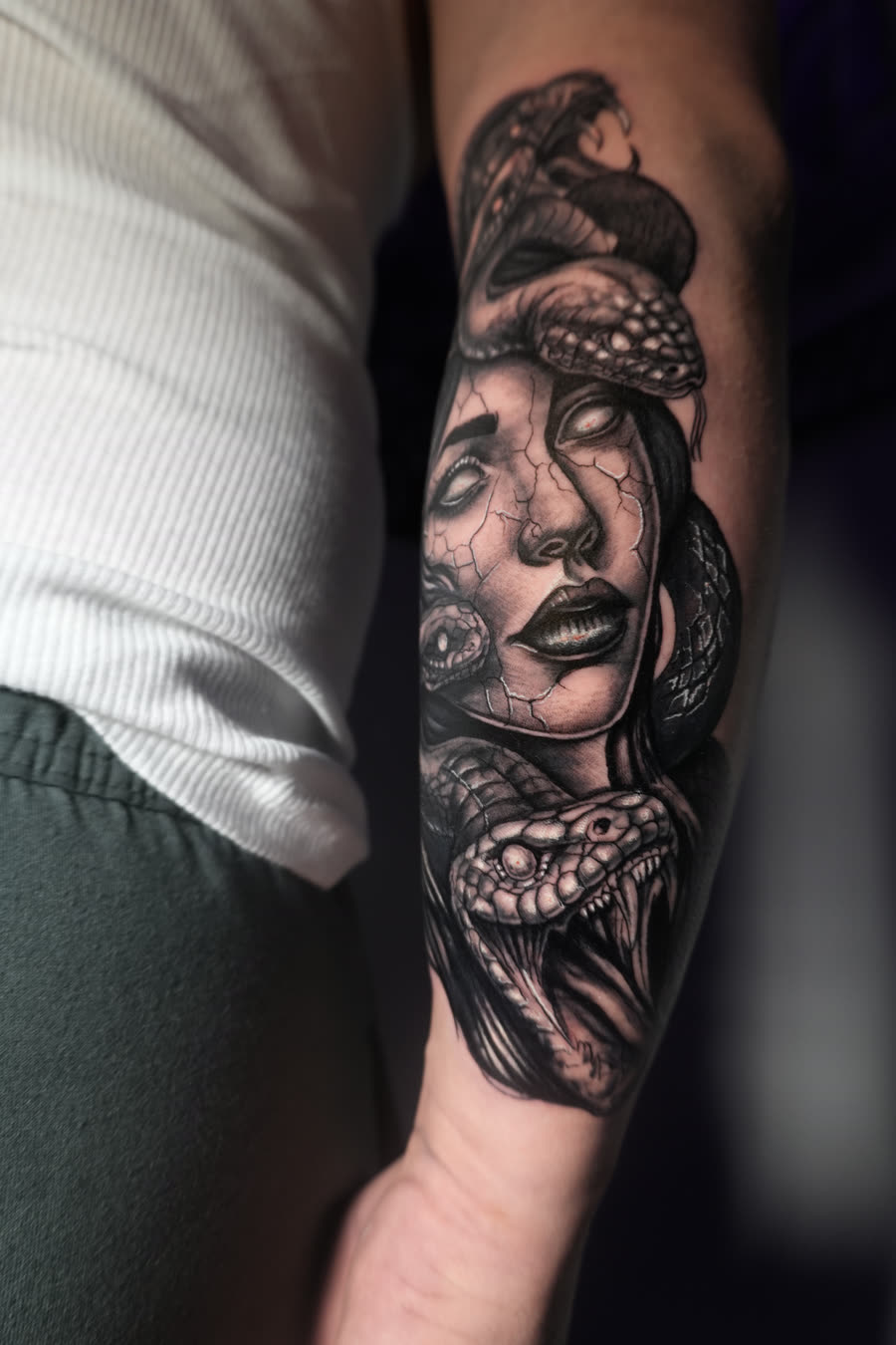 Medusa con ojos blancos y serpientes en antebrazo